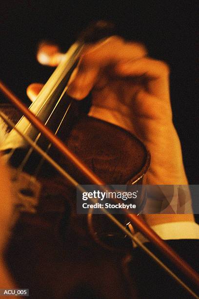 hand on neck of violin, bow across strings - klassische orchestermusik stock-fotos und bilder