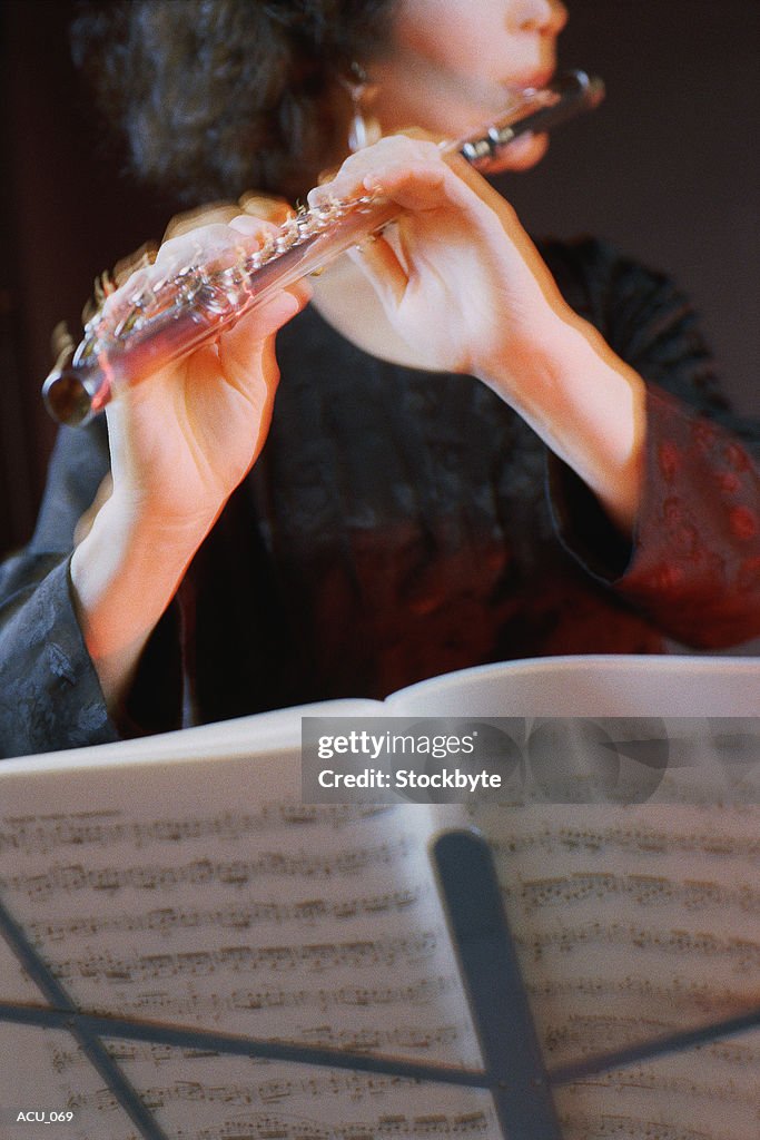 Woman playing flute; sheet music in foreground