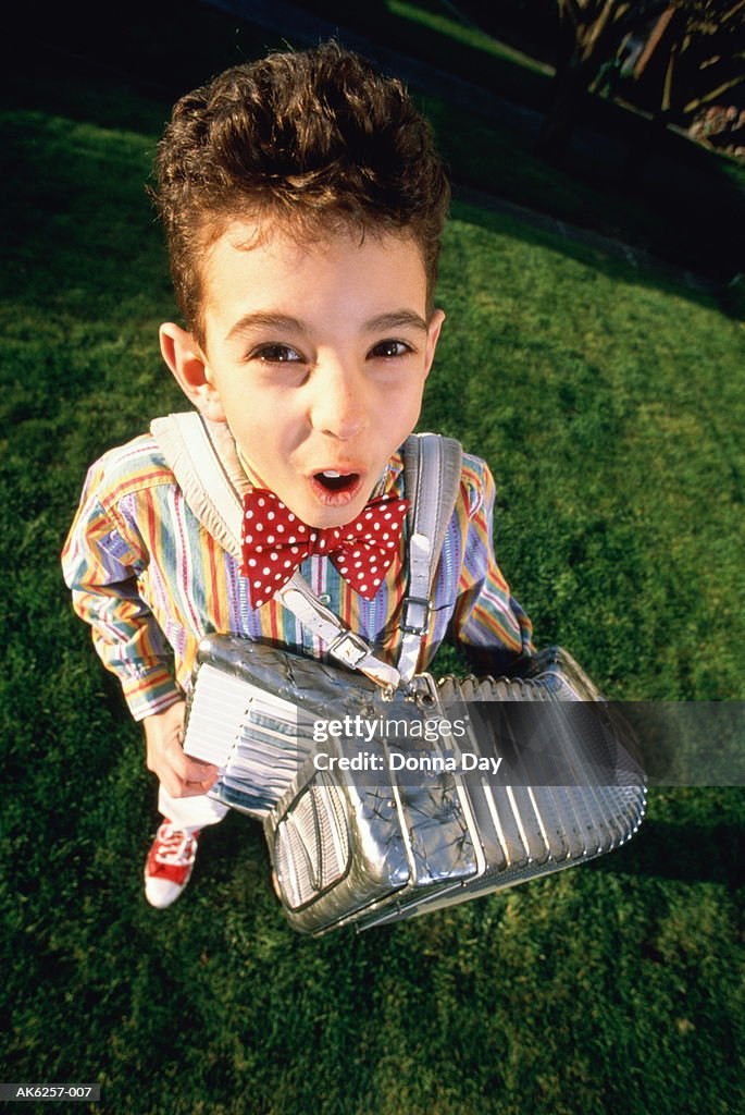 Boy (7-9) playing accordion in backyard, elevated view