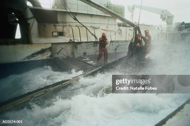 crewmen standing on deck of trawler during rough seas - bering sea fotografías e imágenes de stock