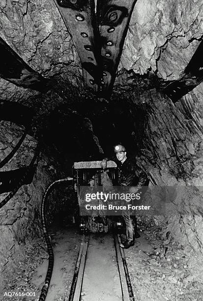 miner standing beside mining train in tunnel, usa (b&w) - ondergrond stockfoto's en -beelden