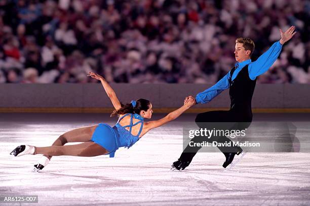 figure skating pair performing in front of crowd (digital composite) - kunstschaatsen stockfoto's en -beelden