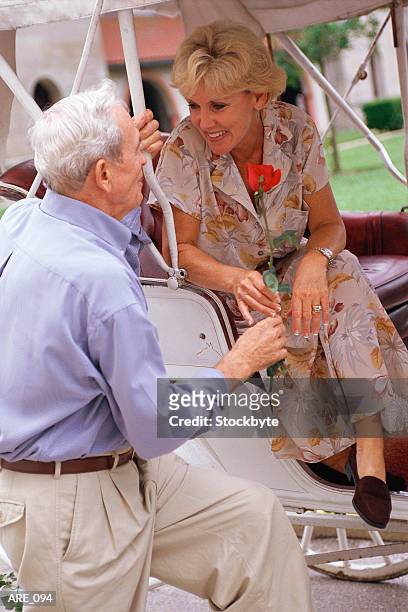 man giving rose to woman in carriage - enkele roos stockfoto's en -beelden