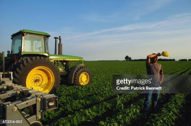 soya bean farmer in field with tractor, wiping brow, indiana, usa - champs tracteur photos et images de collection