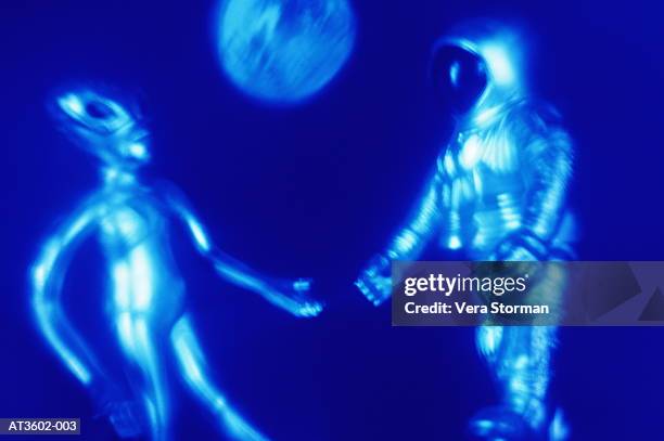 toy astronaut and alien, close-up (blue tone, multiple exposure) - secret handshake stock pictures, royalty-free photos & images