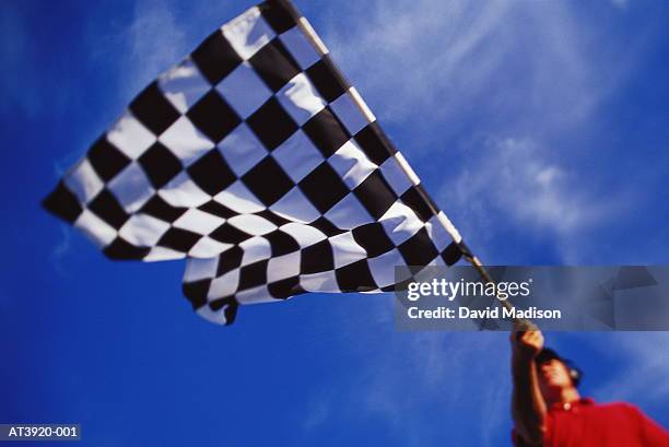 motor racing official waving chequered flag, low angle view - línea de meta fotografías e imágenes de stock