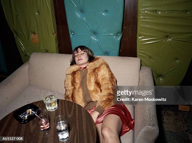 young woman passed out on sofa in bar, drinks on table, elevated view - alcolismo foto e immagini stock