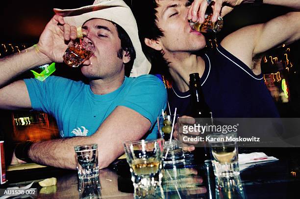 young men drinking shots in bar, close-up, low angle view - alcohol abuse stock pictures, royalty-free photos & images