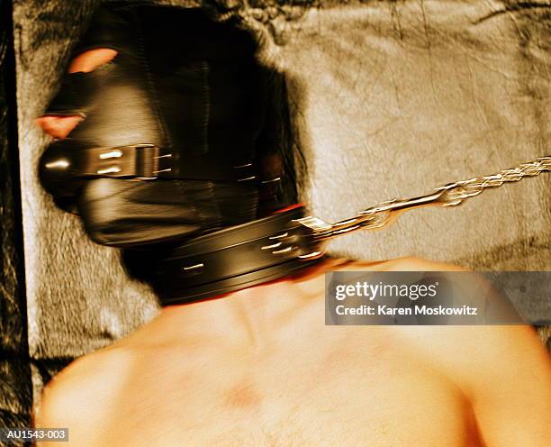 young man wearing leather mask and leash, close-up (blurred motion) - fetisjkleding stockfoto's en -beelden