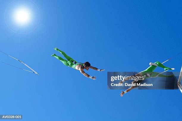 trapeze artists performing under blue sky, view from below - trapeze artists stock pictures, royalty-free photos & images