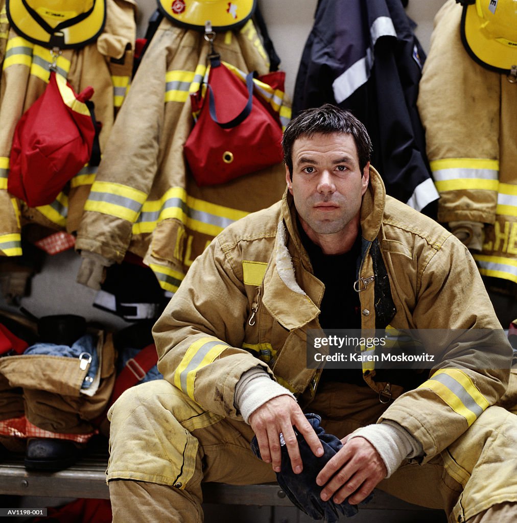 Male firefighter wearing protective clothing, sitting