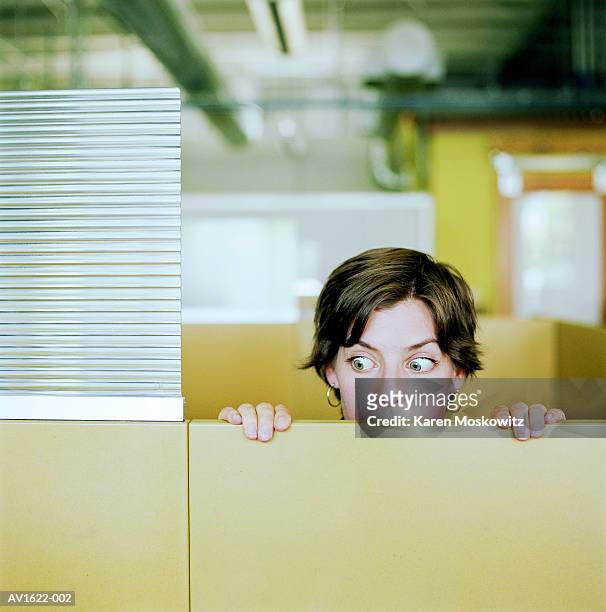 businesswoman peering over cubicle wall - neugierde stock-fotos und bilder