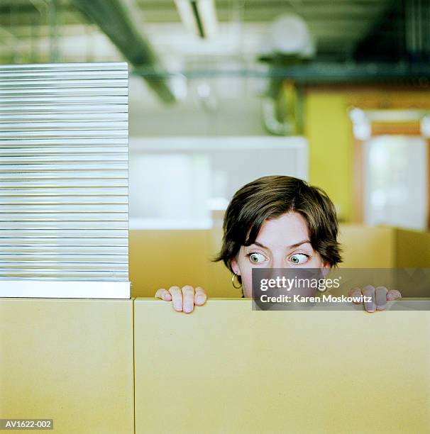 businesswoman peering over cubicle wall - gluren stockfoto's en -beelden