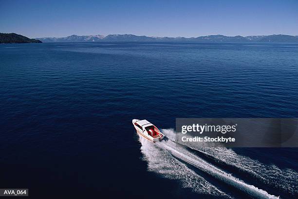 distant shot of motorboat speeding across lake - motorboot varen stockfoto's en -beelden