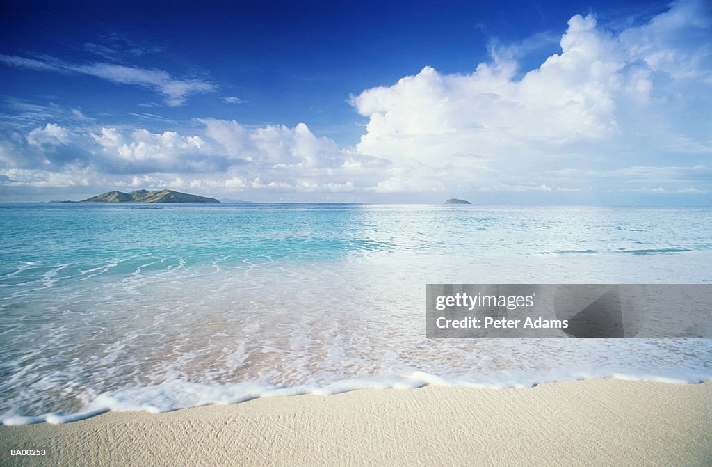 Fiji, Mana Island, waves foaming on sandy beach