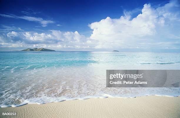 fiji, mana island, waves foaming on sandy beach - peter island stock pictures, royalty-free photos & images