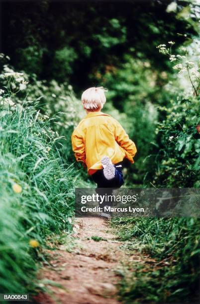 boy (5-7) running on path, rear view - marcas stock-fotos und bilder