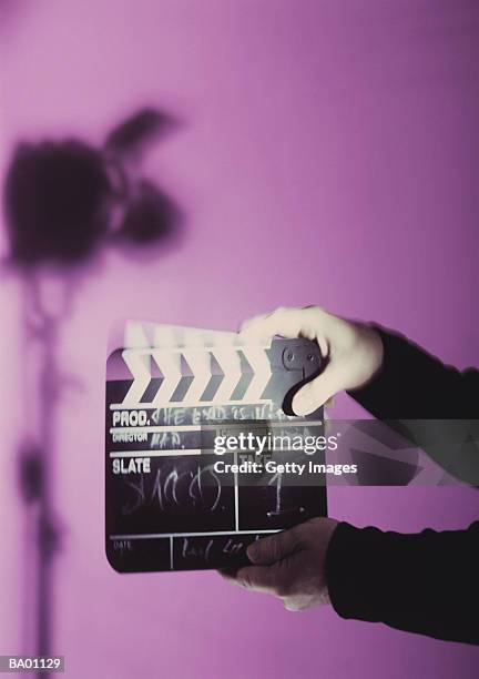 hands holding film slate, studio light silhouette in background - filmstudio stockfoto's en -beelden