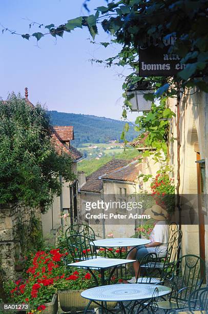 woman sitting at outdoor cafe overlooking village, elevated view - french cafe stock-fotos und bilder
