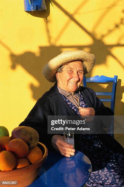 greece, crete, senior woman sitting with drink outdoors, portrait - crete woman stock pictures, royalty-free photos & images