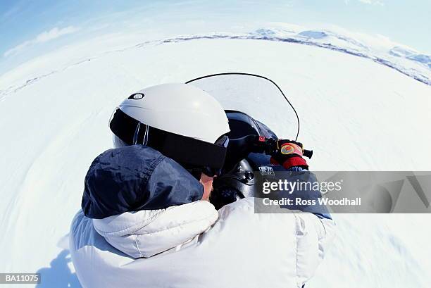 person driving snowmobile, rear view (wide angle) - ross woodhall stock-fotos und bilder