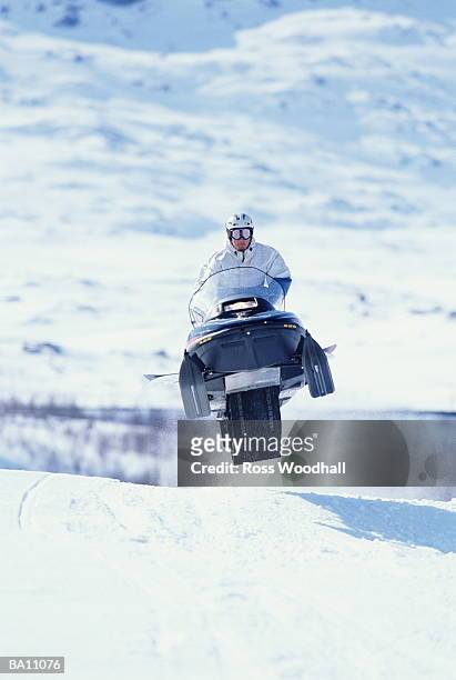person driving snowmobile across snowfield - ross woodhall stock-fotos und bilder