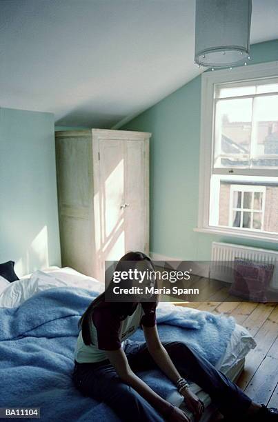 young woman sitting on bed, portrait, elevated view - maria stockfoto's en -beelden