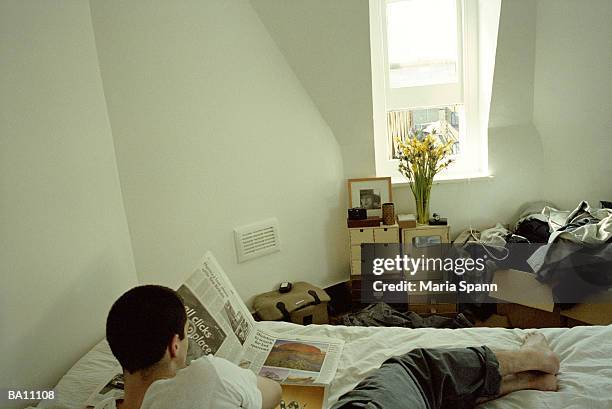 young man reading newspaper in bed, rear elevated view - marea stock pictures, royalty-free photos & images