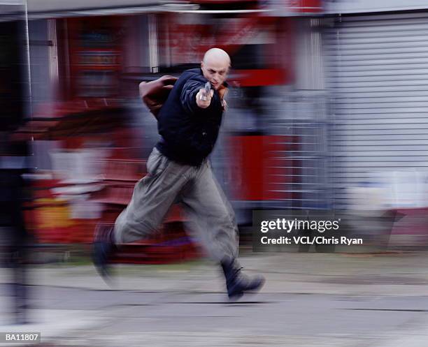 man pointing gun, while running - bankräuber stock-fotos und bilder