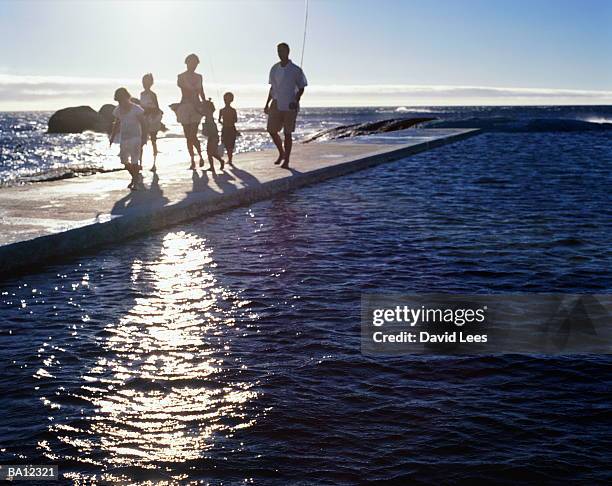 family of six walking along jetty by sea - familie mit vier kindern stock-fotos und bilder