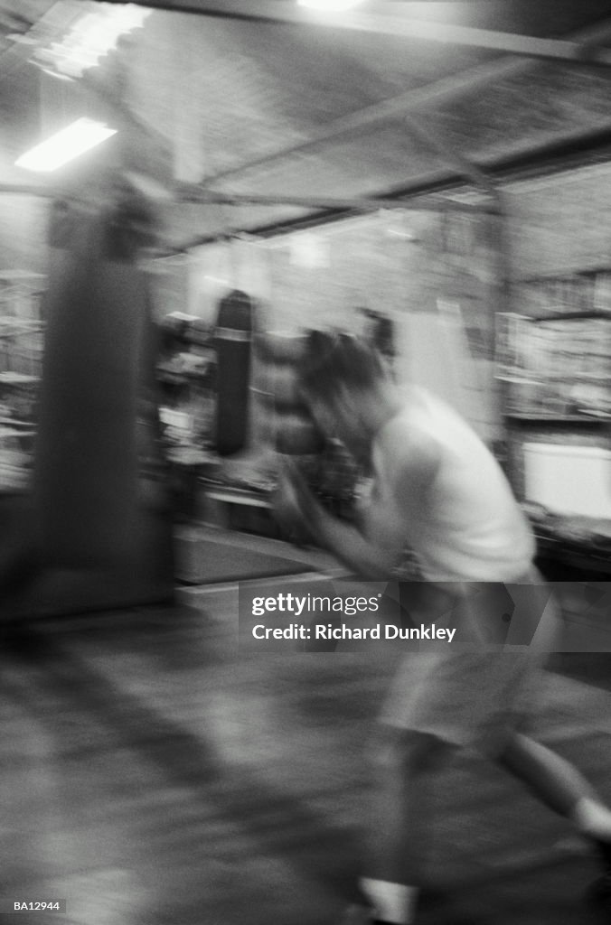 Boxer training on heavy bag in gym (blurred motion, B&W)