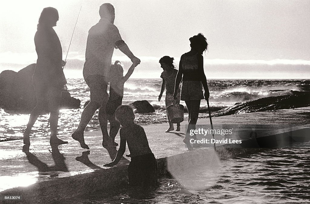 Family of six walking along jetty, rear view (B&W)