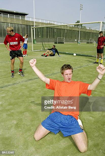 soccer player celebrating after scoring, kneeling on pitch - nur erwachsene stock-fotos und bilder