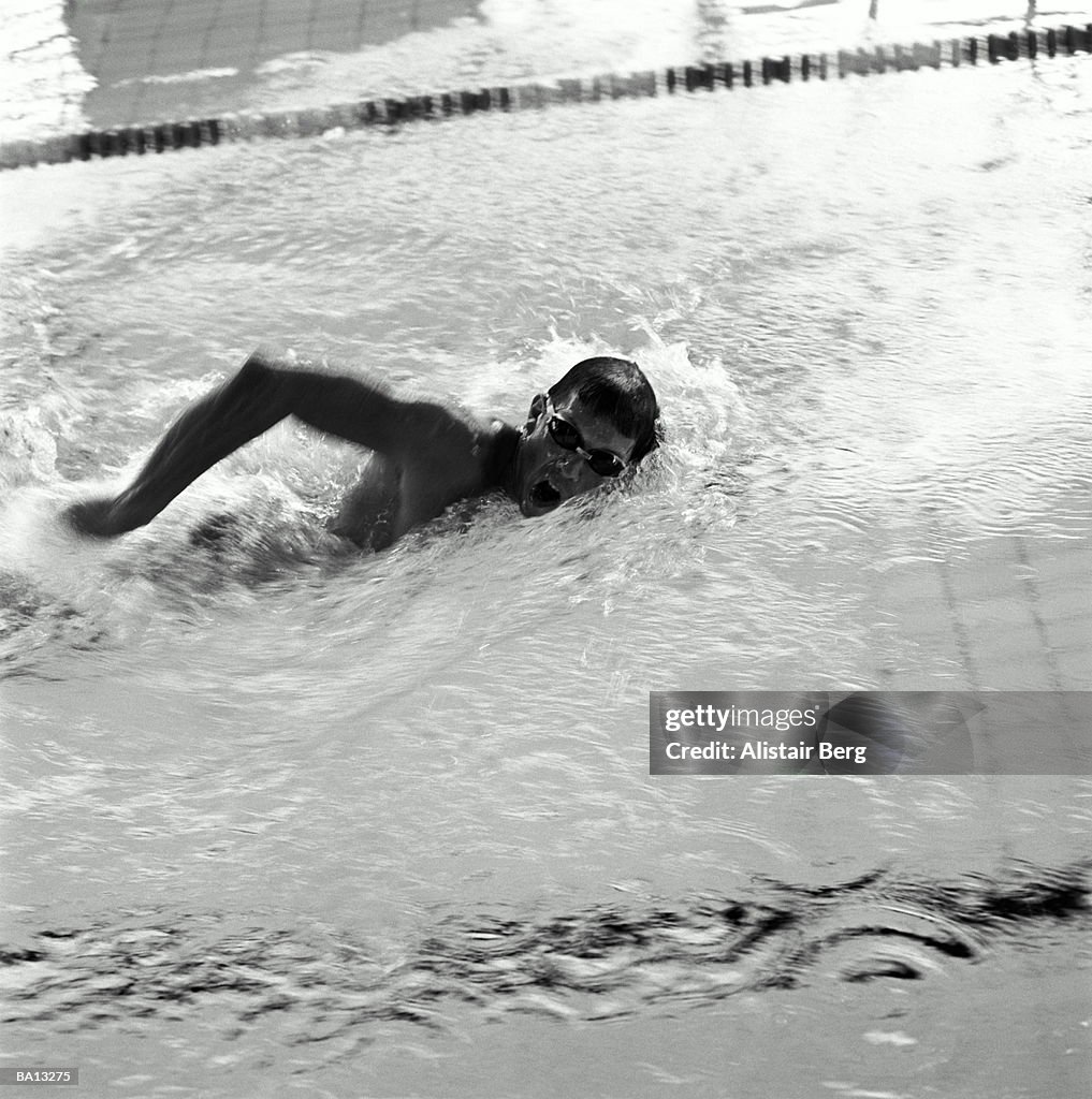 Man swimming in pool, doing front crawl, elevated view (B&W)