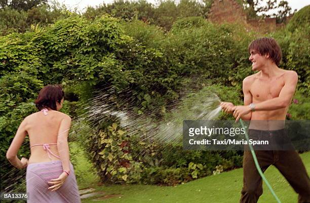young man spraying woman with hose - maria stock pictures, royalty-free photos & images