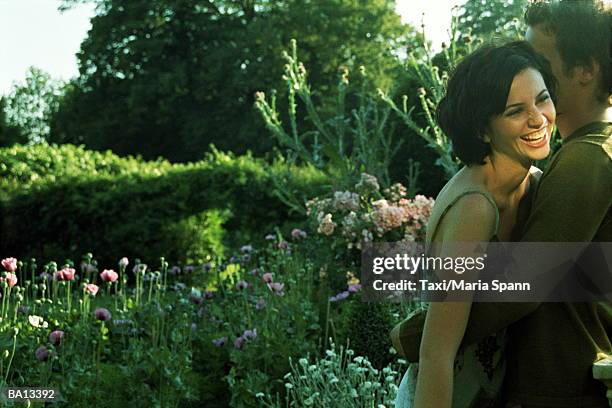 young couple embracing in garden, woman laughing - marea stock pictures, royalty-free photos & images