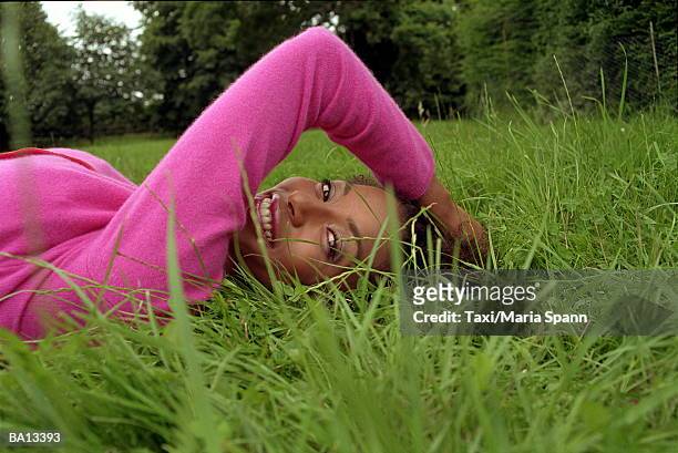 young woman lying on grass, smiling, portrait, close-up, ground view - maria stockfoto's en -beelden