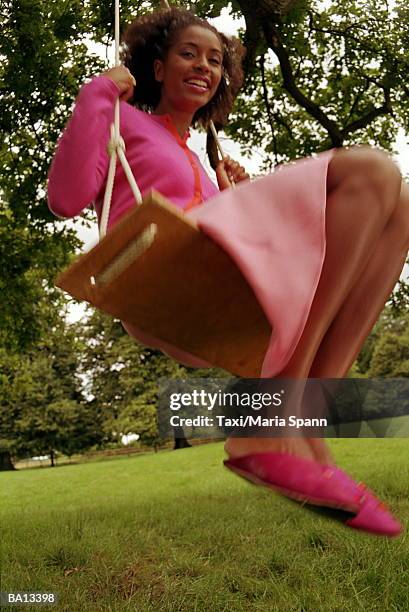 young woman on tree swing, portrait, low angle view - maria stockfoto's en -beelden