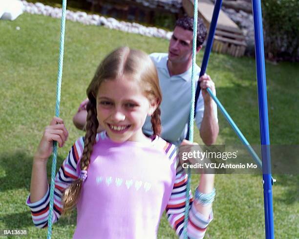 girl (8-10) on swing, father in backround - antonio stock pictures, royalty-free photos & images