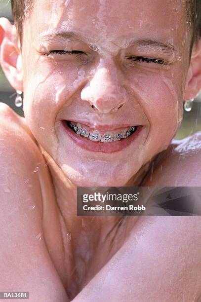 boy (9-11) with braces, water running down face, close-up - cooling down stock-fotos und bilder
