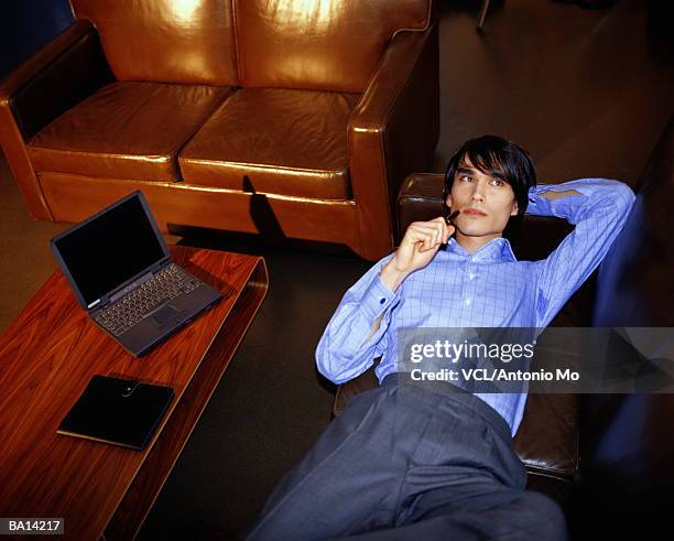 businessman lying on sofa, holding pen, elevated view - antonio stock pictures, royalty-free photos & images
