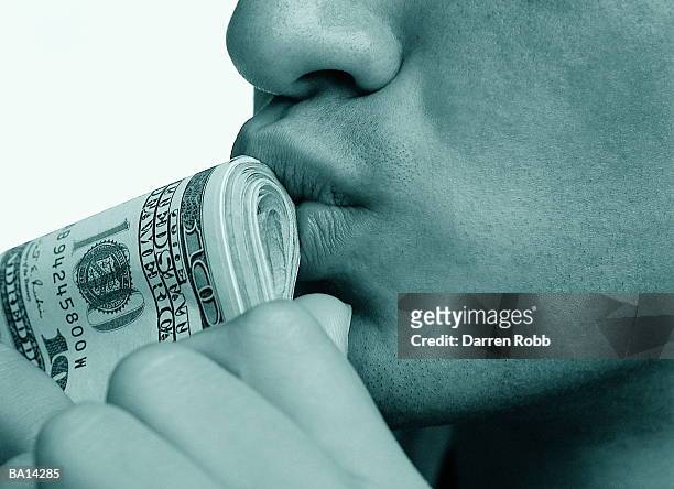 man kissing folded american dollar bills, close-up (b&w) - yuppie stock-fotos und bilder