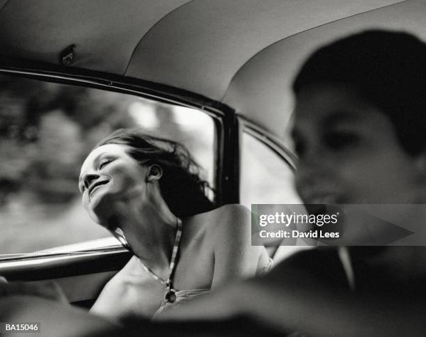 two women in back of car (focus on woman with head out window( (b&w) - 亂髮 個照片及圖片檔