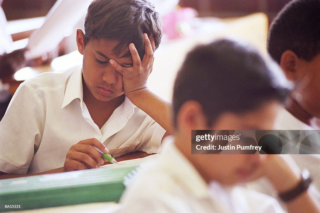 School classroom, focus on boy (10-12) with head in hands