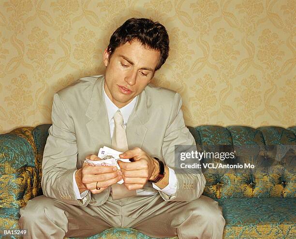 man counting money on sofa, close up - homens de idade mediana imagens e fotografias de stock