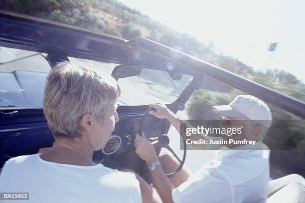 mature couple in open top 4 x 4, view over woman's shoulder - open shoulder stock-fotos und bilder