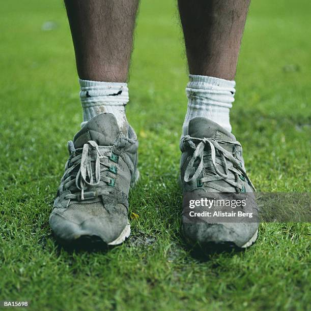 man standing on grass, wearing running shoes, low section - old shoes stockfoto's en -beelden