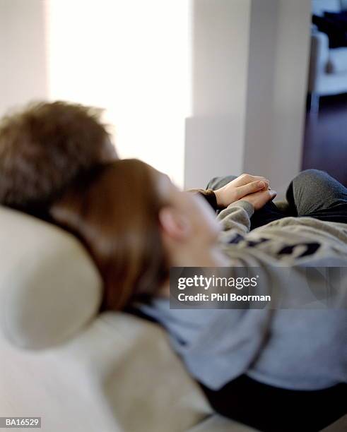 young couple sitting on sofa, holding hands, rear view (soft focus) - couple portrait soft ストックフォトと画像