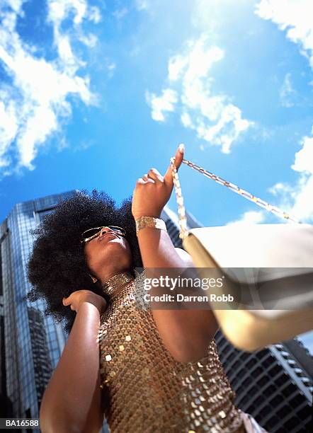 woman swinging gold handbag from finger outdoors, low angle view - sequin dress stock pictures, royalty-free photos & images