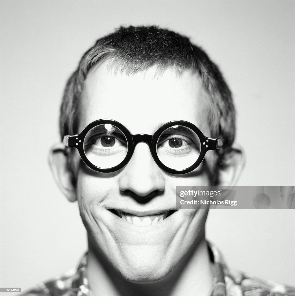 YOUNG MAN WEARING THICK RIMMED ROUND GLASSES, PORTRAIT (B&W)
